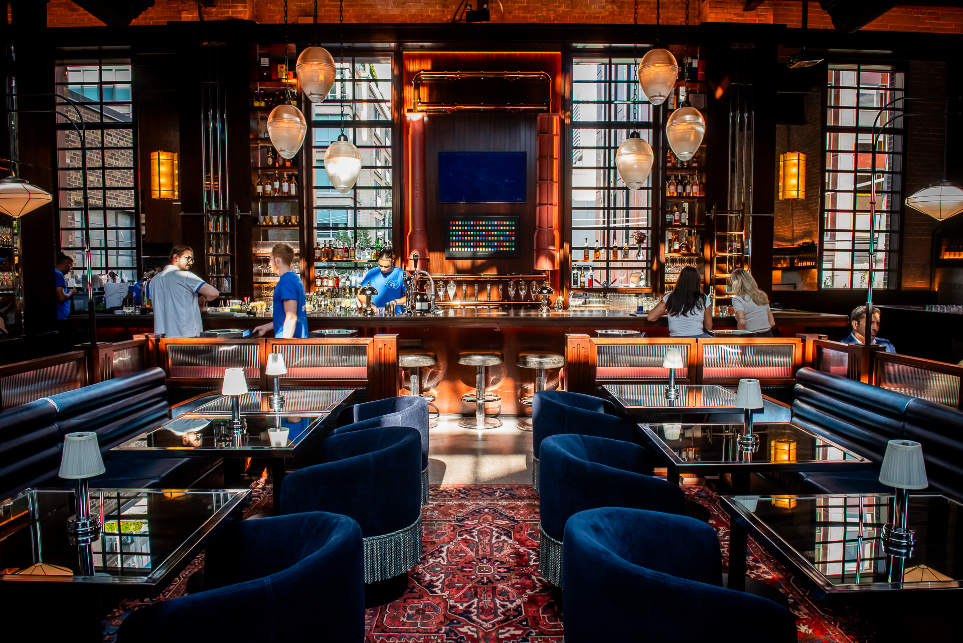 A view of the Civil Works bar featuring an Art Deco style decor, tear drop lamps hanging from the ceiling and a 25 foot long communal bar.