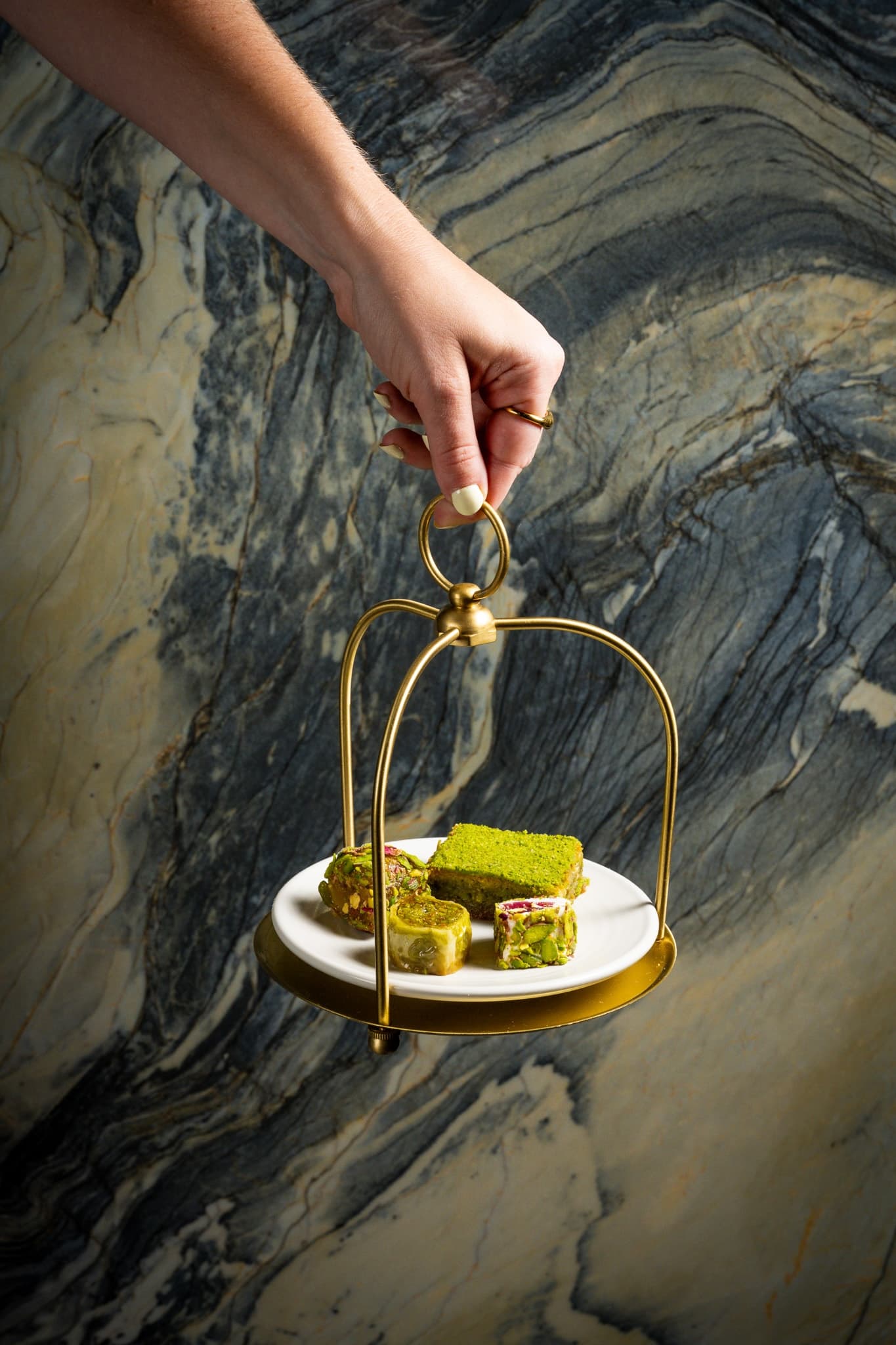 A hand holding a tray of Turkish desserts