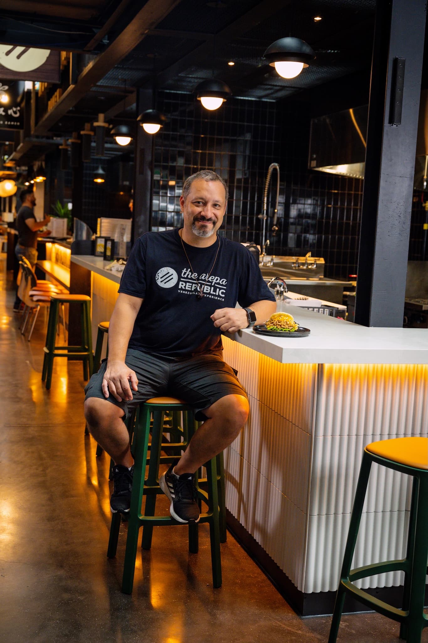 Luis Manuel Cordo, owner of the Arepa Republic sitting a stool outside of his food stall.