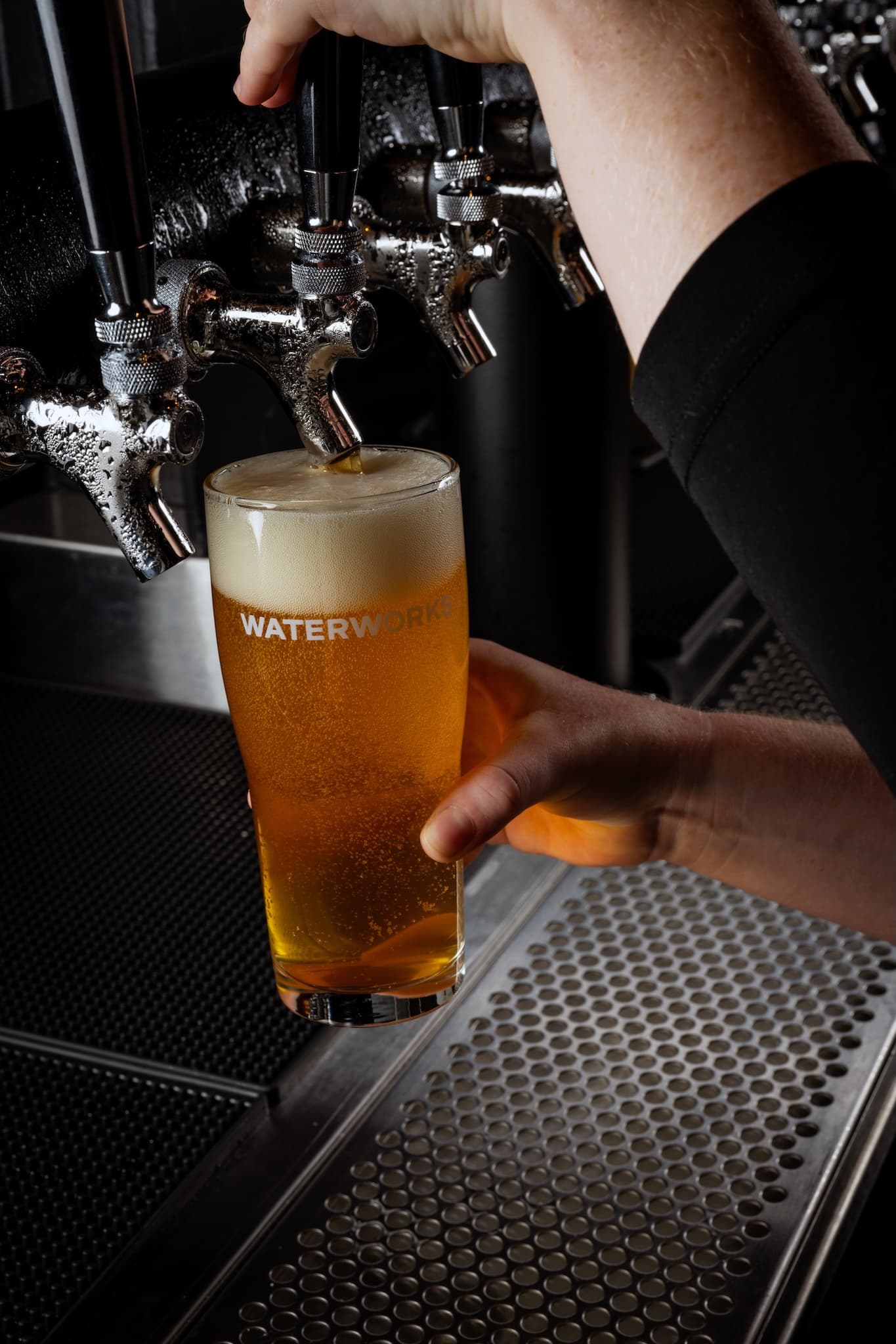 Bartender pouring a draft pint of lager into a glass