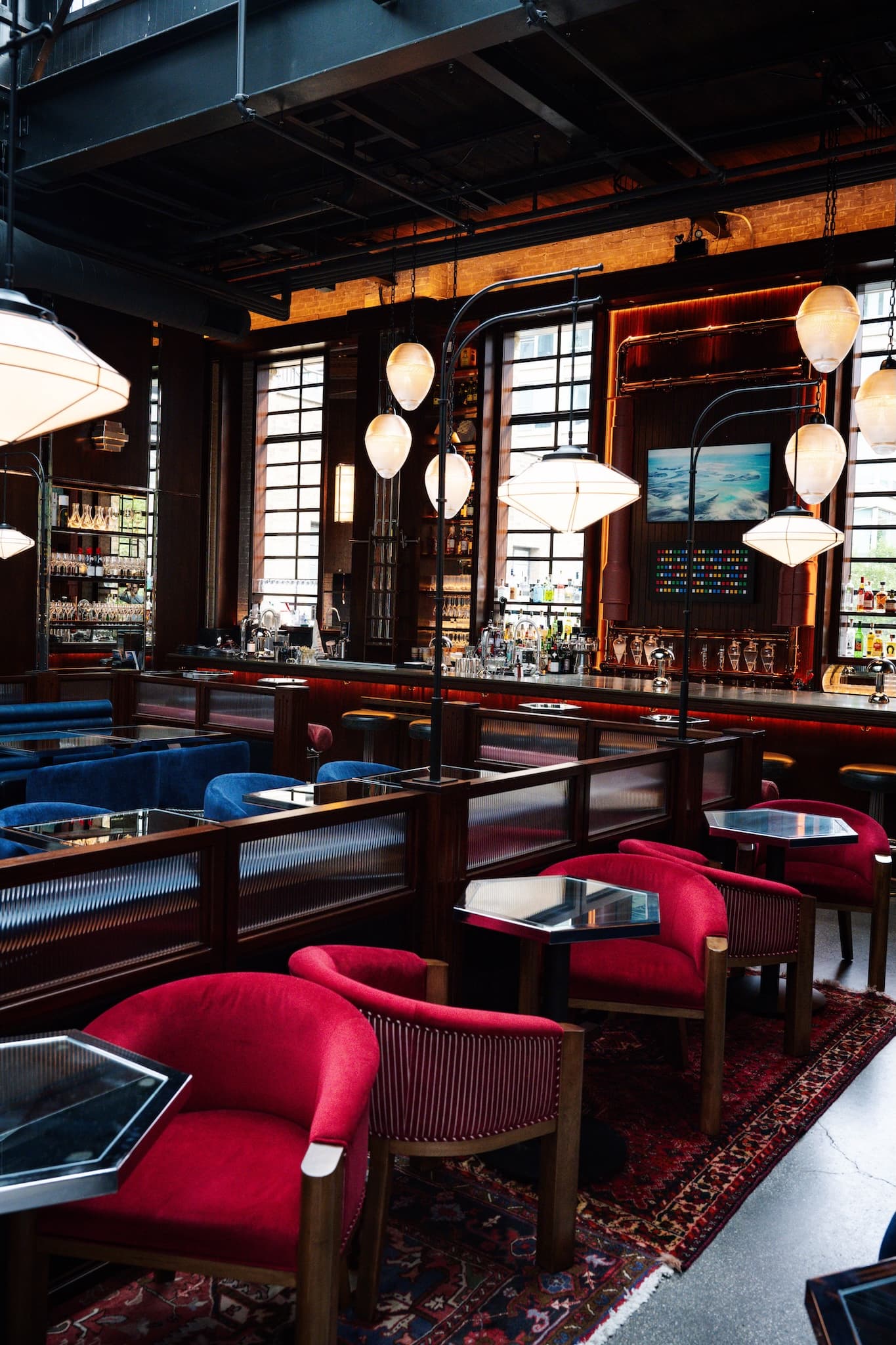 View of the bar in the background and the red velvet club chairs in the foreground.