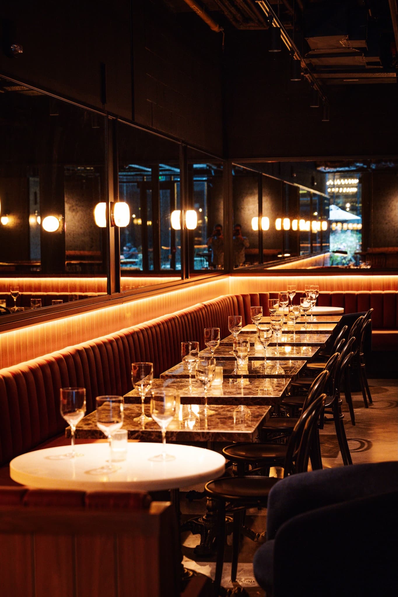 Leather banquette seats with square, grey mottled marble tables and black chairs.