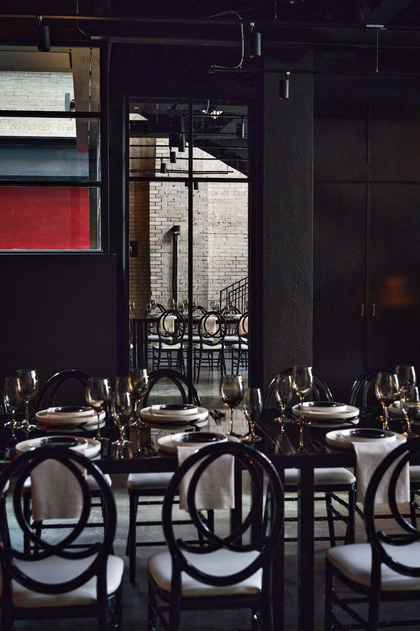 Side view of table set for dinner and the reflection of the chairs in a mirror on the far wall.