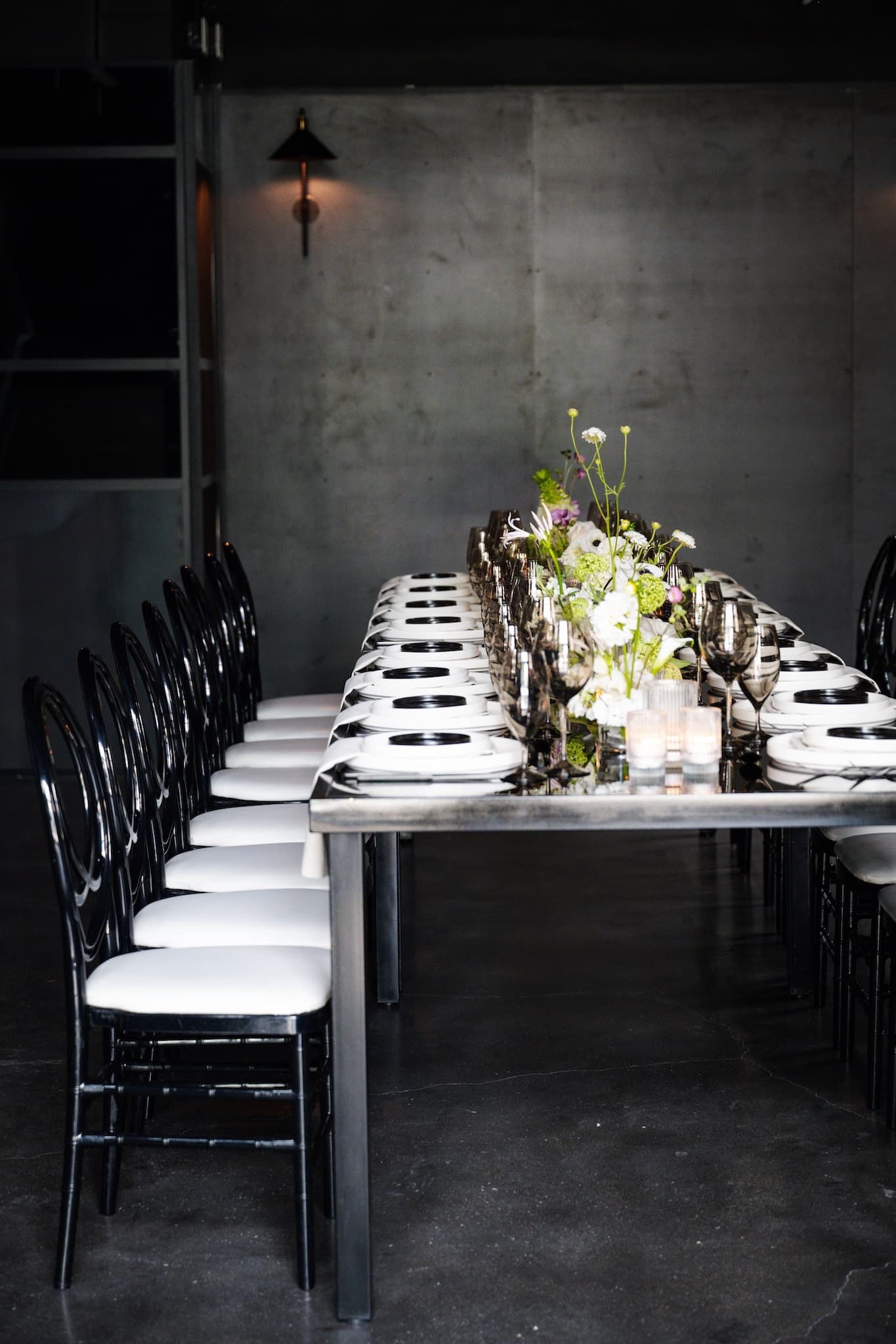 Side view of long rectangular black table and black chairs set for 16.