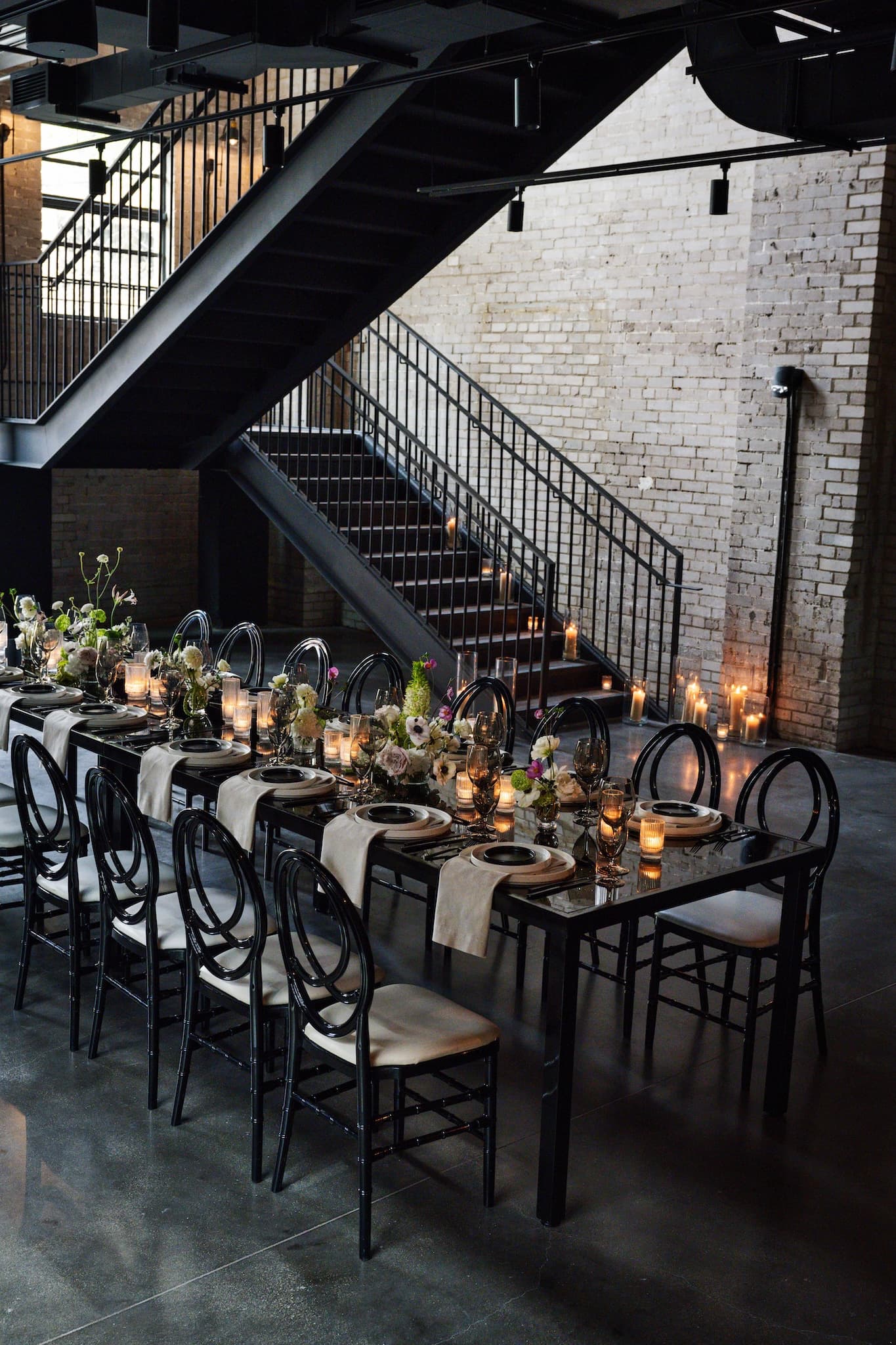 Long rectangular table set for 16, with black chairs