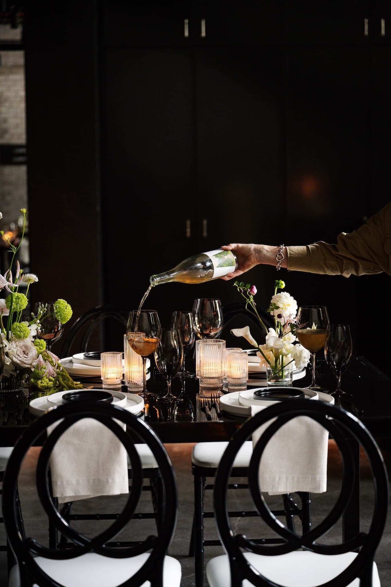 Side view of two chairs in front of a modern table setting of white napkins and white and black dinnerware