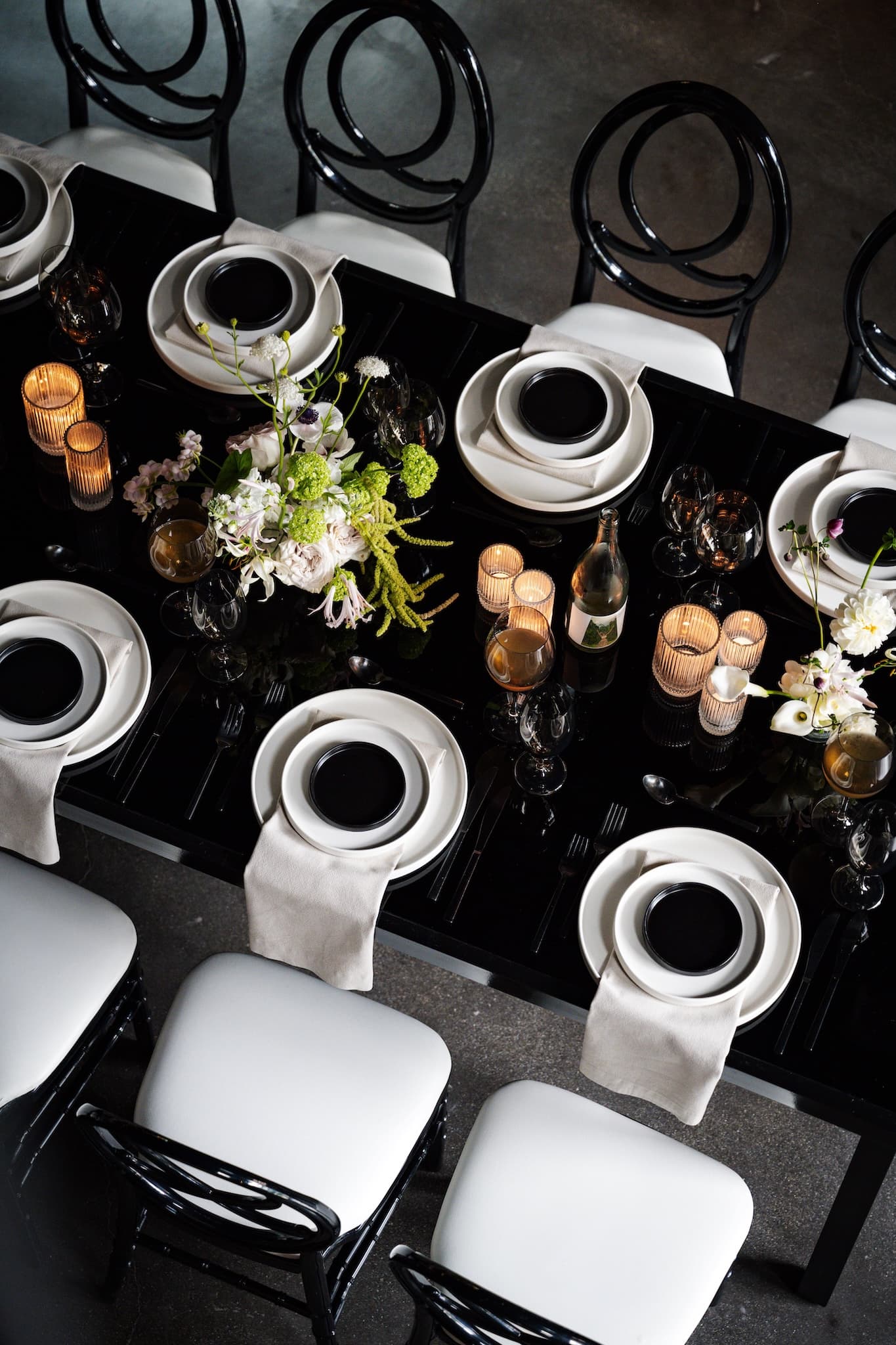 Top view of black table with white and black dinnerware and white napkins