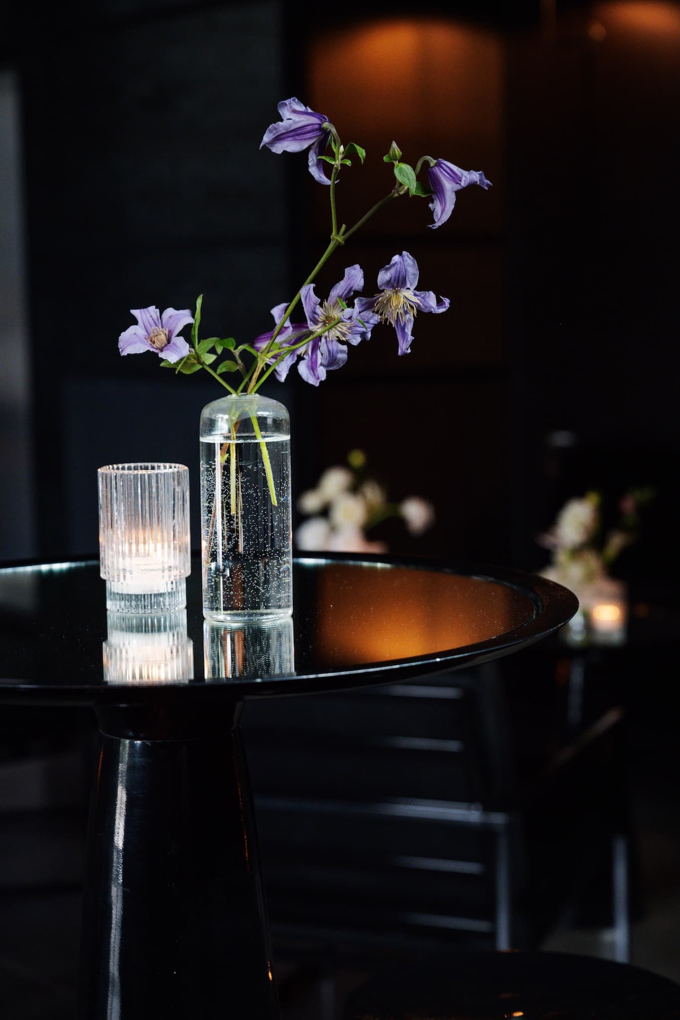 Purple flowers in a clear vase sitting on a black cruiser tabletop.