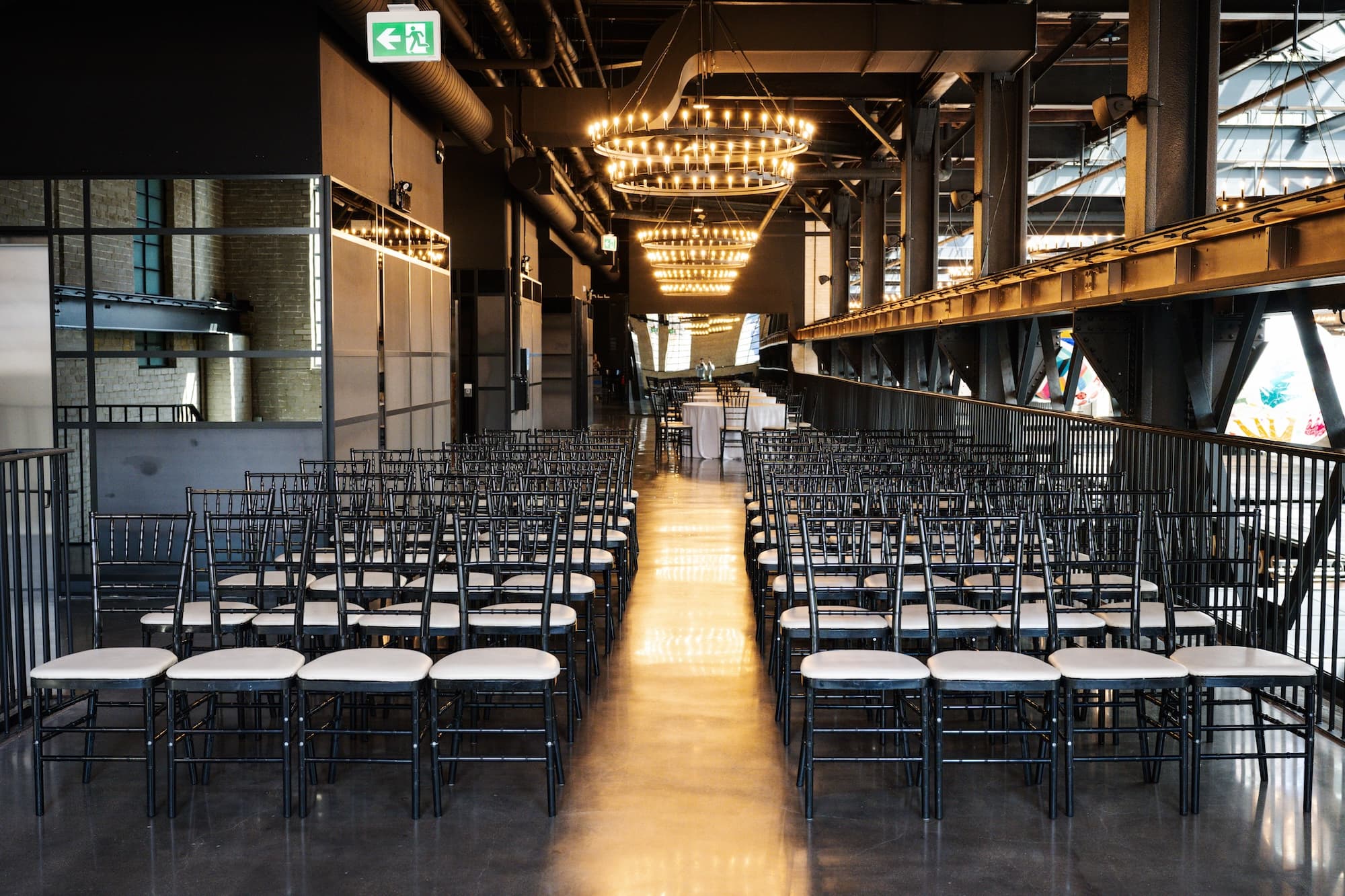 Meeting set up in the West Hall event space, showing two rows of chairs set beneath large two-tier steel chandeliers.