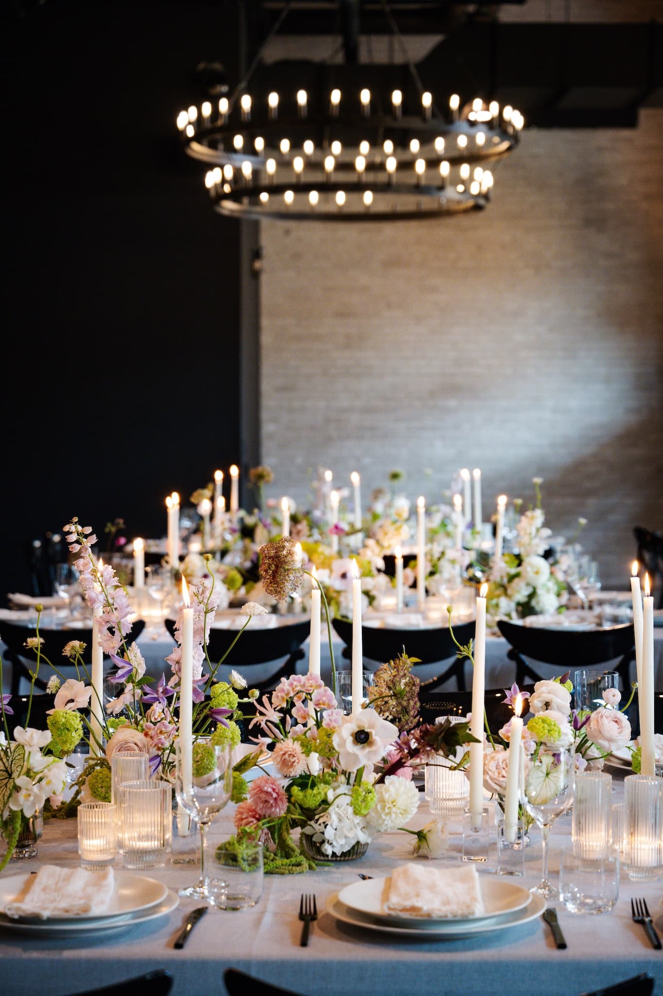 Table setting for a formal dinner with taper candles, flowers, wine glasses and place settings