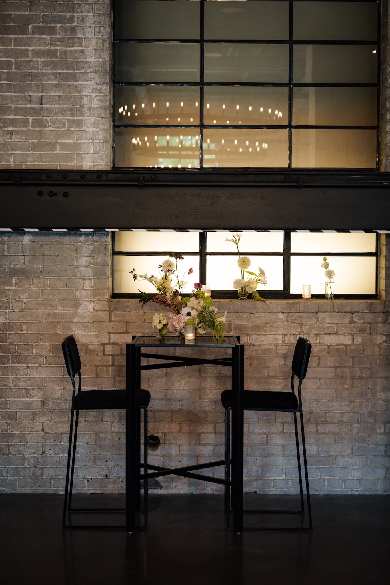 Black square cruiser table and two black chairs against the yellow brick wall.