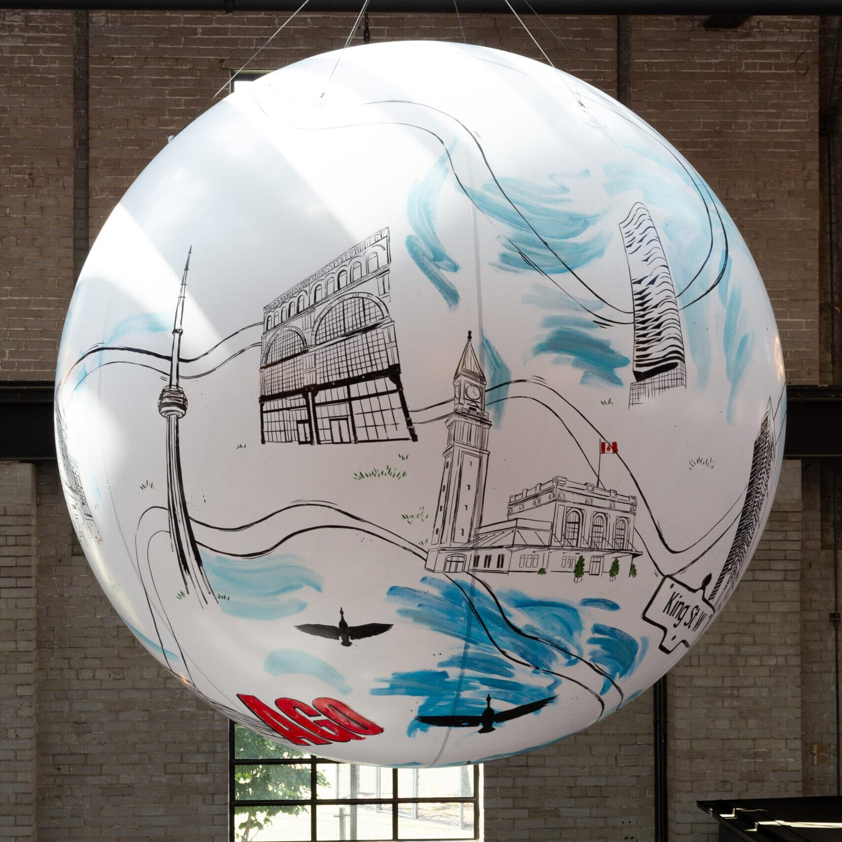 A 3-meter wide painted sphere, showing iconic illustrated images of Toronto's landmark buildings and cityscape, and hanging high over the food hall.