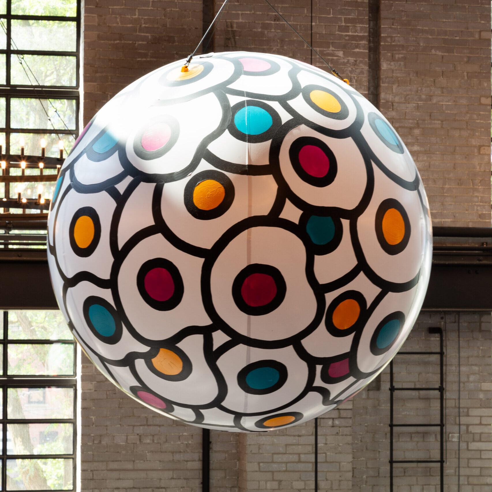 A painted sphere, of colourful fried eggs, hanging from the rafters of the food hall.