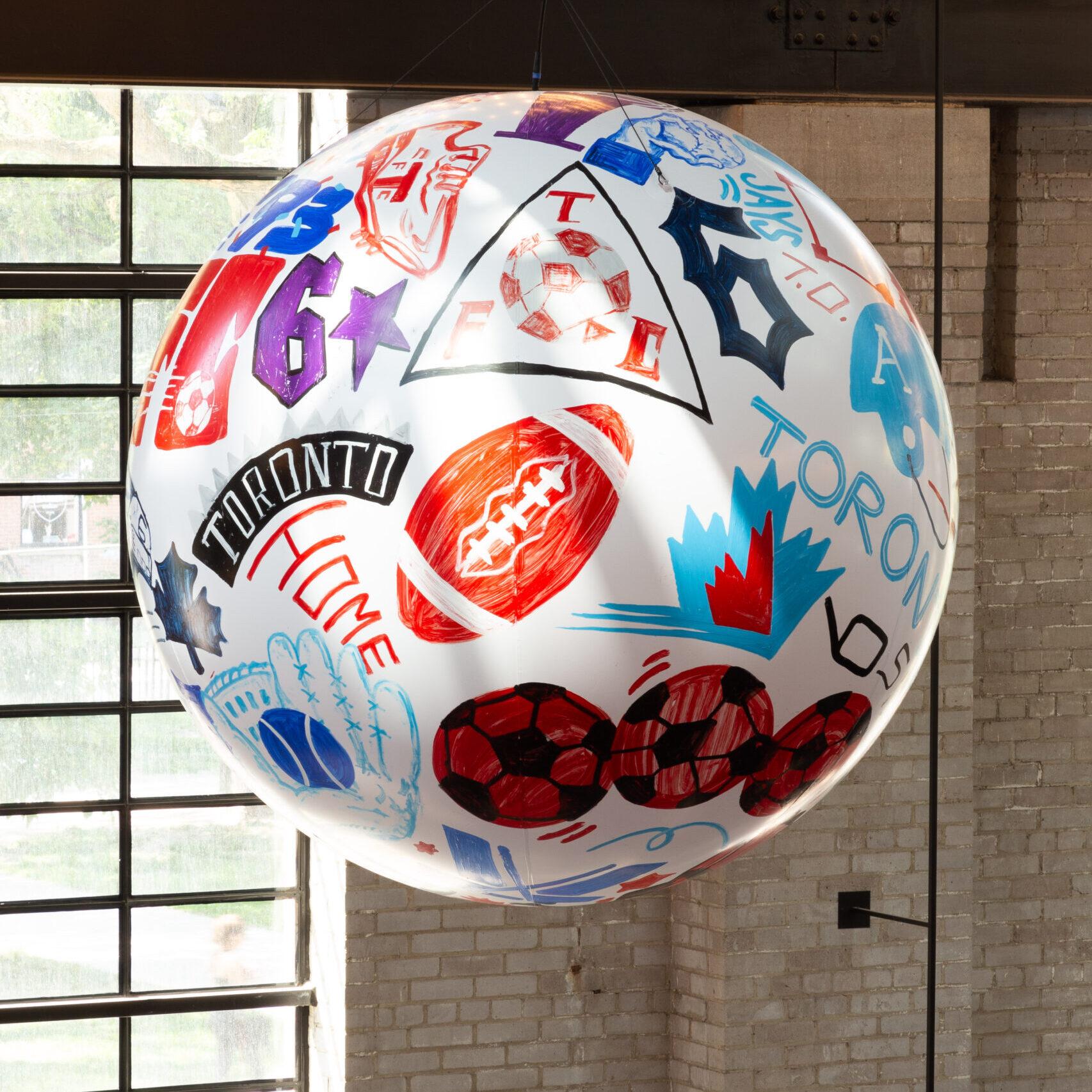 A painted sphere, with Toronto sports related images, hanging high from the rafters of the food hall.