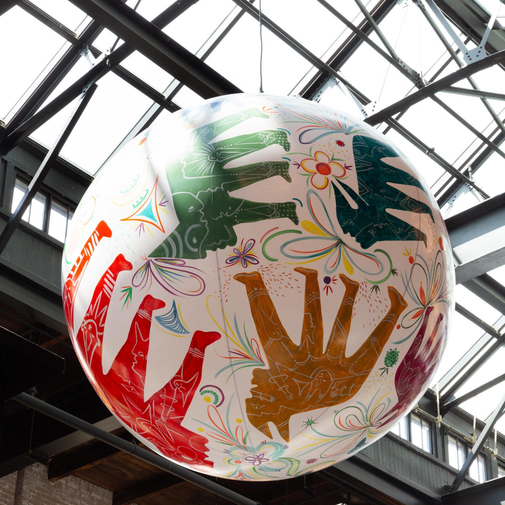 A painted sphere, of animals in the springtime, hanging from the rafters of the food hall.