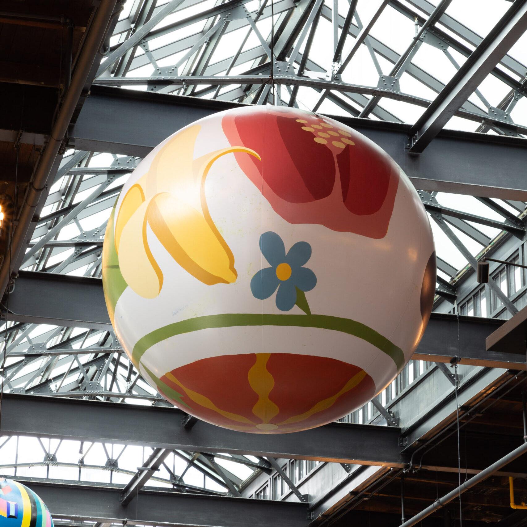 A painted globe, showing painted vegetable, hanging high from the rafters of the food hall.