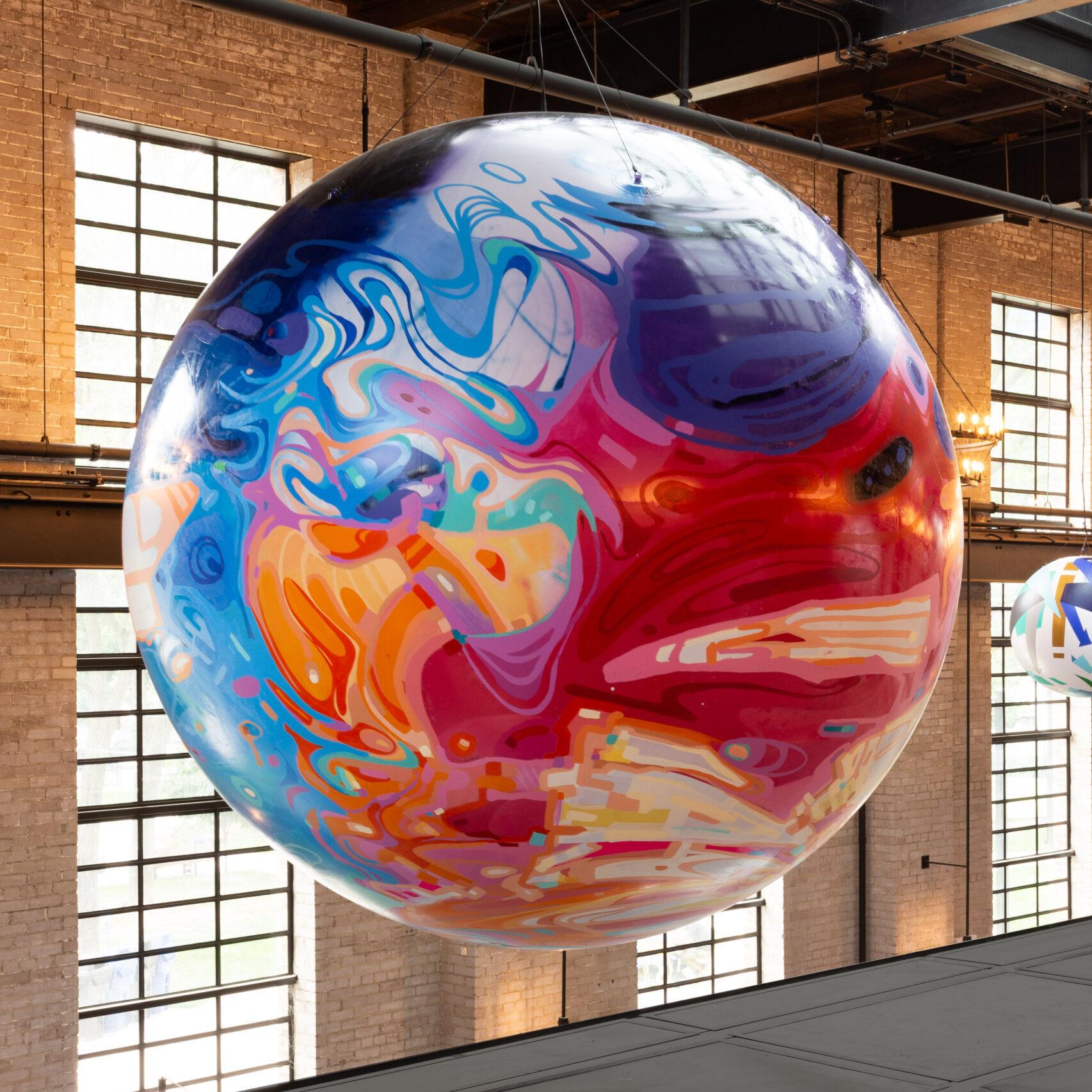 A beautiful colourful painted sphere hanging from the ceiling of the food hall.