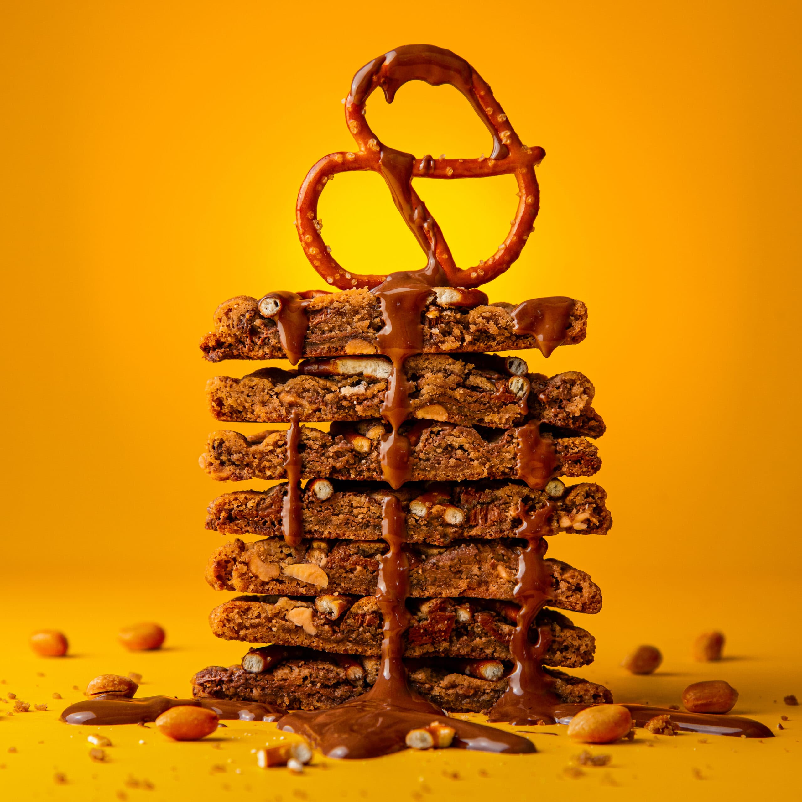 Stack of peanut, chocolate and pretzel cookies with a pretzel perched on the top of the stack.