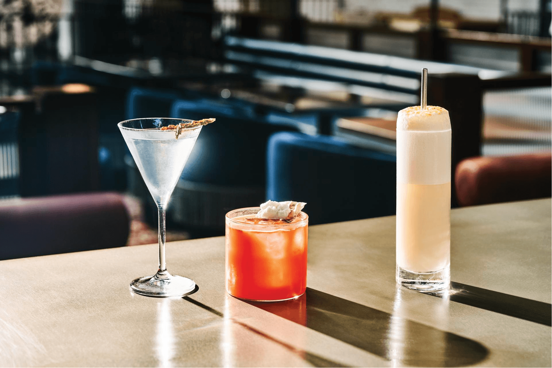 Three cocktails on the bar at Civil Works: one in a martini glass, one in a whiskey glass and one in a highball.